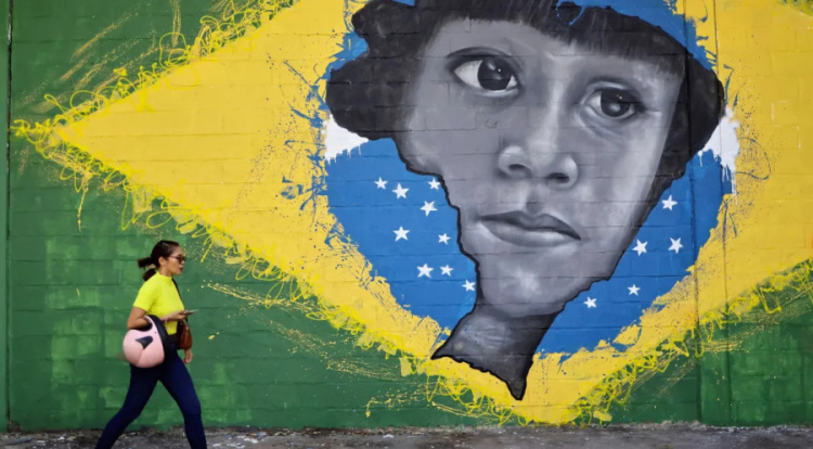 Mulher passa por grafite com bandeira do Brasil e mapa nacional com rosto de indígena, em Belém, Pará • 04/08/2023REUTERS/Ueslei Marcelino